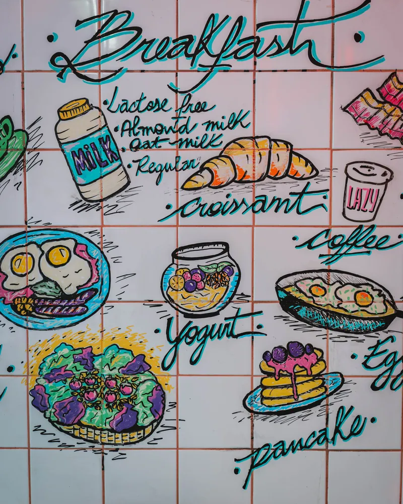 Mural pintado à mão nos azulejos do Lazy, com o menu de pequeno-almoço